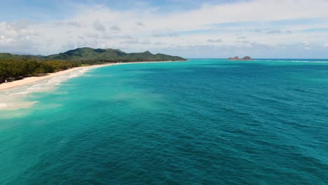 Drone-Vuela-Sobre-El-Océano-Azul-En-Un-Día-Caluroso-Con-Una-Tranquila-Playa-Tropical-Hawaiana-Y-Mini-Islas-A-La-Vista