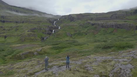 Ascending-aerial-drone-shot-showing-tourist-visiting-idyllic-Seven-Tier-Waterfall-in-Iceland---Cinematic-drone-footage-during-cloudy-day