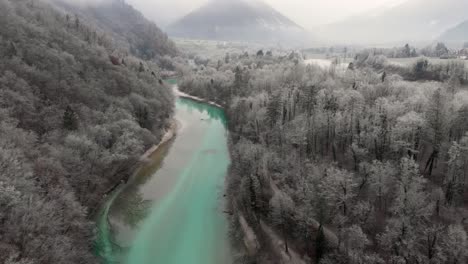 Wunderschöner-Türkisfarbener-Fluss-Fließt-Friedlich-Am-Nebligen-Wintermorgen,-Aus-Der-Luft
