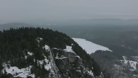 Fliegen-Sie-In-Den-Rocky-Mountains-Mit-Einem-Mann-Davon,-Der-Im-Winter-In-Quebec,-Kanada,-Auf-Der-Spitze-Steht