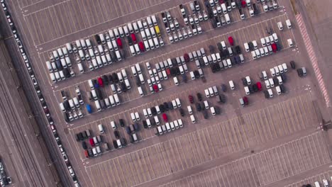 Top-down-view-of-new-cars-parked-in-outdoor-depot-at-industrial-harbor