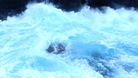 Drone-close-up-of-rough-ocean-wave-white-wash-crashing-against-a-cliff-face