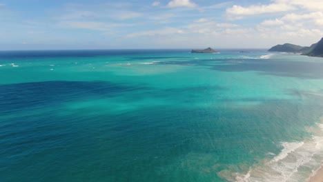 Die-Drohne-Steigt-Am-Hawaiianischen-Strand-Herab,-Während-Sie-Sich-Umdreht,-Um-Den-Ozean-Mit-Einer-Mini-Insel-In-Der-Ferne-Zu-Betrachten