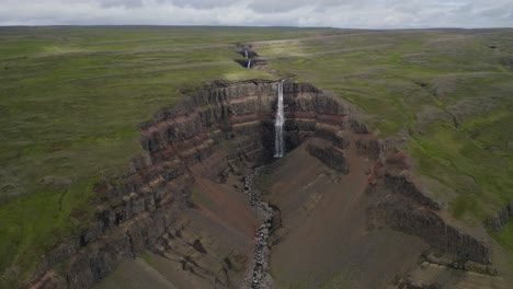 Filmischer-Rückwärtsflug,-Der-Den-Atemberaubenden-Wasserfall-Hengifoss-Und-Die-Grüne-Landschaft-Islands-Zeigt