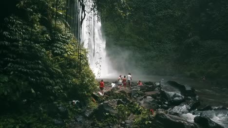 Bali,-Spring-2020-in-1080-60p,-Daytime,-cinematic-drone-flight-slow-motion-flight-in-front-of-the-waterfall-over-the-river-from-left-to-right-You-see-a-small-group-tourists