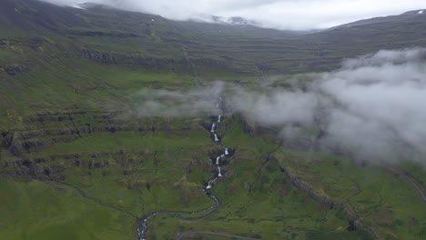 Toma-Aérea-De-Hermosas-Cascadas-De-Siete-Niveles-En-Islandia-Durante-Un-Día-Nublado-Rodeado-De-Montañas-Con-Vegetación