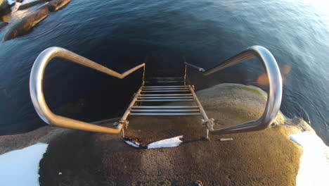4k-Close-up-of-a-metal-staircase-by-the-very-cold-ocean-water-at-Gothenburg,-Sweden