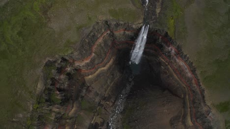 Aerial-top-down-shot-of-steep-deep-ravine-with-falling-waterfall-in-Iceland-during-daytime---Epic-Hengifoss-Waterfall-in-giant-crater-valley
