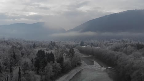 aerial-view-of-small-river-and-valley-on-frosty-winter-morning,-gloomy-cold-vibes
