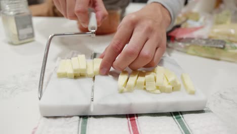 A-person-cutting-mozzarella-cheese-using-a-cheese-cutter-block-in-slow-motion,-static-close-up
