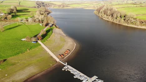 Aerial-Over-Wimbleball-Lake-On-Exmoor-In-Somerset-With-Empty-Boats-Beside-Pier