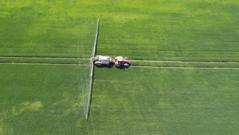Aerial-trucking-shot-of-the-agricultural-sprayer-spraying-insecticide-to-the-green-field-agricultural-works-on-spring