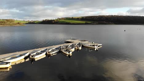 Aerial-Flying-Over-Pier-With-Empty-Boats-Moored-At-Wimbleball-Lake-On-Exmoor-In-Somerset