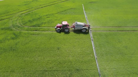 Aerial-trucking-shot-of-the-industrial-sprayer-working-on-the-green-field-agricultural-works-on-spring