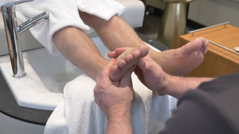 Foot-Massage,-Masseur-Massaging-The-Sole-Of-A-Man-At-Nail-Lounge-And-Salon