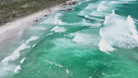 Aerial-birdseye-view-of-a-kite-surfers-skimming-across-green-water-near-the-Cape-of-Good-Hope,-South-Africa