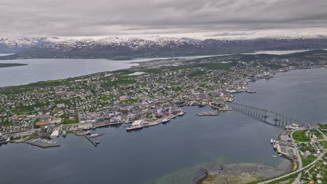 Tromsø-Norway-Aerial-v15-high-angle-panoramic-panning-view-capturing-scenic-snowy-mountain-landscape,-tromsøya-island-and-tromsdalen-downtown-cityscape---Shot-with-Mavic-3-Cine---June-2022