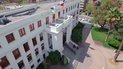 Aerial-drone-view-of-Ã‘uÃ±oa-City-Hall-colonial-building-with-chilean-flag-fluttering