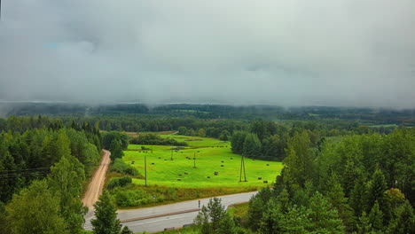 Timelapse-of-clouds-moving-over-green-country-landscape-and-road-junction,-high-angle-view