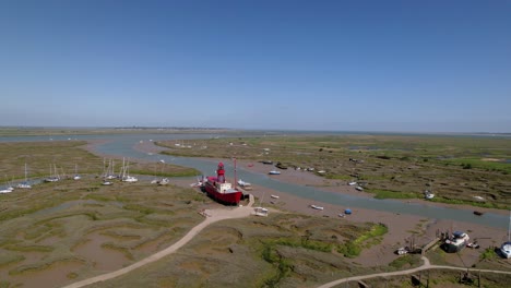 Aerial-view-around-a-Lightship-stuck-during-the-low-tide,-sunny-Tollesbury,-UK---orbit,-drone-shot
