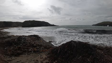 Slow-motion-ocean-waves-splashing-around-large-rock-Anglesey-shoreline
