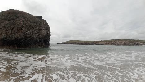 Ocean-waves-splashing-around-large-rock-island-on-Anglesey-coastline-Slow-motion
