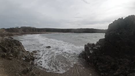 Ocean-waves-splashing-around-large-rock-coastline-on-Anglesey-Slow-motion