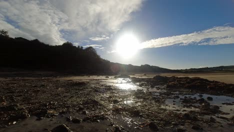 Time-lapse-shimmering-sunset-sand-beach-clouds-passing-above-woodland-coastline-dolly-right