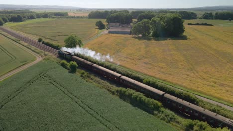 Aerial-view-of-a-steam-engine-locomotive-train-passing-on-tracks-in-the-countryside-in-England