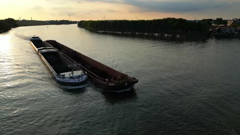 Cargo-ship-with-barges-connected-on-side-slowly-moving-on-calm-river