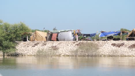 Vista-De-Campamentos-Improvisados-Vistos-Desde-El-Otro-Lado-Del-Río-En-Sindh,-Pakistán