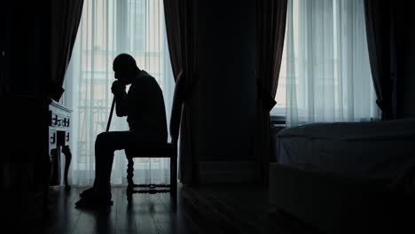Silhouette-of-old-man-sitting-in-his-bedroom-alone-feeling-lonely,-loneliness-concept