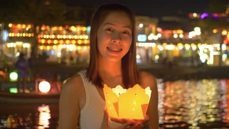 Traditional-lantern-lights-up-face-of-Asian-tourist-at-night---Hoi-An-riverfront