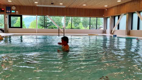 Boy-with-autism-playing-and-flapping-hands-alone-in-swimming-pool---Static-clip-showing-boy-having-fun-and-doing-weird-hand-movements