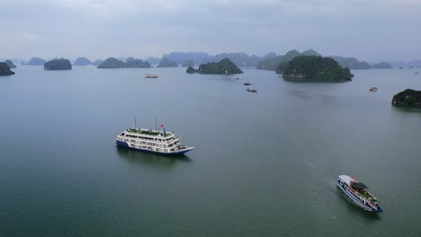 Antenne-Von-Vietnamesischen-Kreuzfahrtschiffen,-Die-Touristen-In-Ha-Long-Bay-Vietnam-Mit-Tropischem-Wasser-An-Einem-Bewölkten-Tag-Befördern