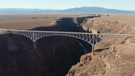 Scenic-aerial-view-of-large-bridge-across-deep-desert-river-gorge