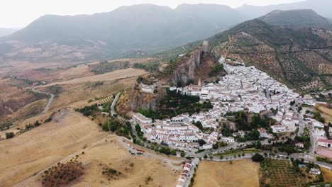 aerial-shot-medieval-castle-and-watchtower-on-top-of-a-mountain-white-houses-traditional-town
