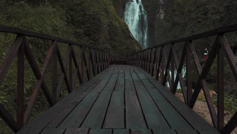 Low-Angle-View-Along-Empty-Wooden-Bridge-Leading-To-Peguche-Waterfalls-In-Otavalo