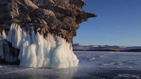 Frozen-lake,-view-on-a-rocky-stone-cliff-with-the-water-in-frozen-state-hanging-from-it