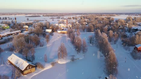 Freezing-small-village-during-snowfall-in-extreme-cold-winter,-aerial-view