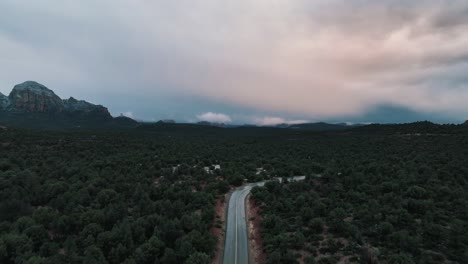 Car-Driving-On-Road-In-Picturesque-Sedona-Arizona-Landscape-On-A-Cloudy-Day---aerial-drone-shot