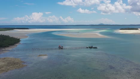 aerial-of-long-pier-extending-far-past-low-tide-on-tropical-turquoise-water-at-Leebong-island-in-Belitung-Indonesia