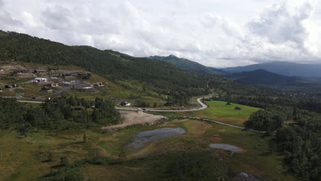 Drone-Se-Mueve-Horizontalmente-Captura-El-Valle-De-Rauland,-Telemark,-Noruega-Y-Un-Pequeño-Asentamiento-En-El-Lateral