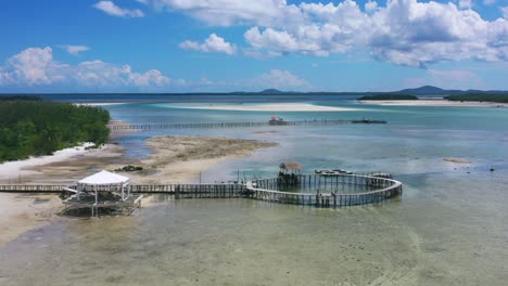 aerial-of-long-pier-and-gazebo-extending-over-sandy-beach-at-low-tide-on-sunny-day-on-Leebong-island-Belitung-Indonesia