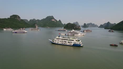 aerial-of-traditional-white-cruise-ship-traveling-through-waters-of-Ha-Long-Bay-Vietnam-around-limestone-mountains-at-sunrise