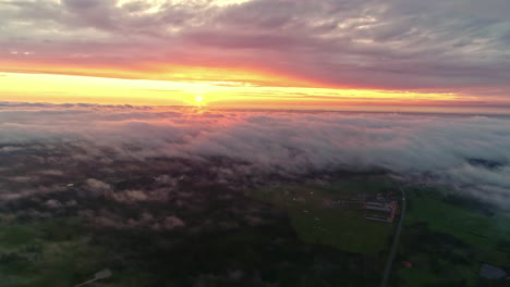 Aerial-of-vivid-sunset-between-two-cloud-layers---cloud-inversion-over-landscape