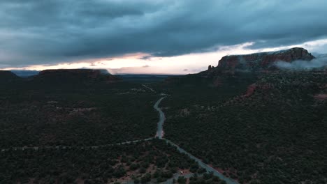 Red-Rock-State-Park-With-Road-Through-Green-Trees-In-Sedona,-Arizona-On-A-Cloudy-Day---aerial-drone-shot