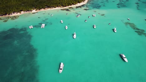 Aerial-view-of-yachts-on-the-coast-of-Punta-Cana,-sunny-Dominican-republic---tilt,-drone-shot