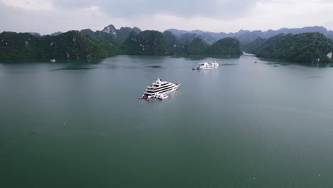 aerial-of-beautiful-limestone-mountain-landscape-in-Ha-Long-Bay-Vietnam-with-mega-yacht-anchored-on-cloudy-day