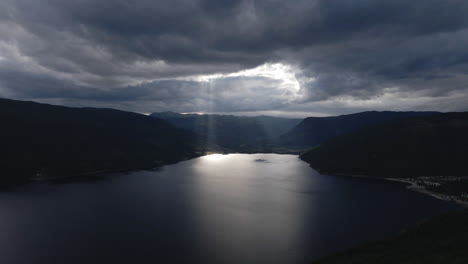 Drone-capture-the-video-of-the-rays-of-light-shine-down-from-a-cloudy-sky-into-a-lake-on-dark-overcast-evening